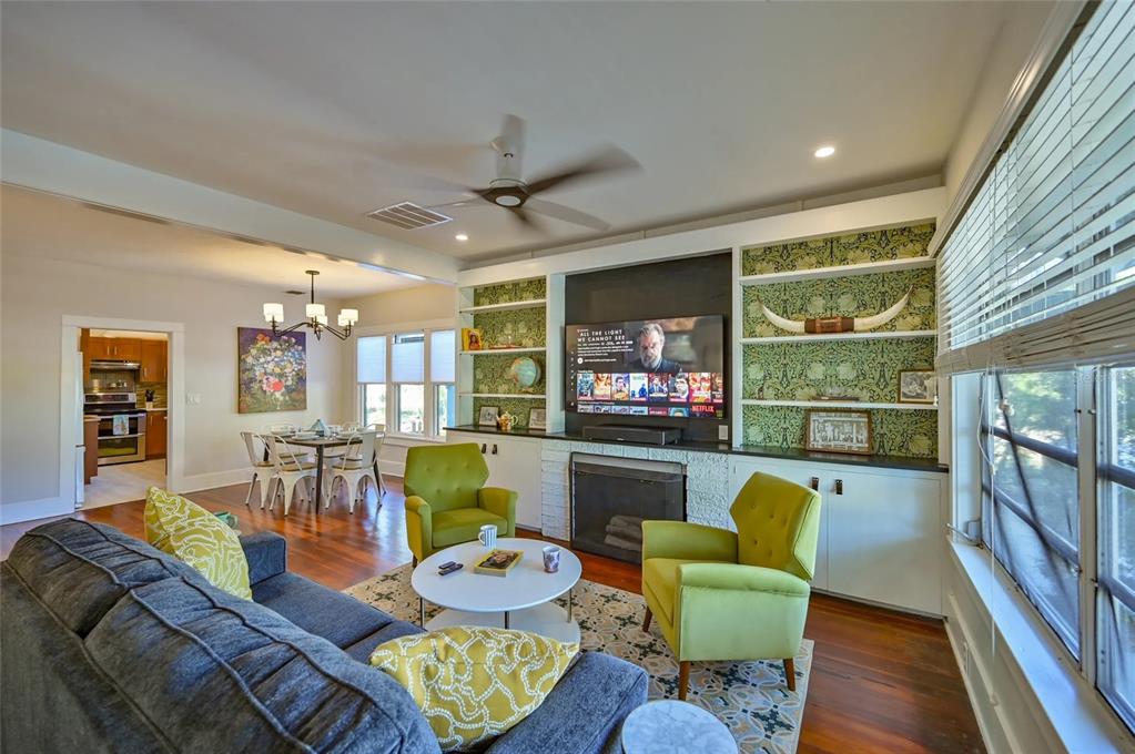 A living room features a fireplace, built-in shelving with patterned wallpaper, and two green chairs — 2408 HILLVIEW STREET, SARASOTA, FL
