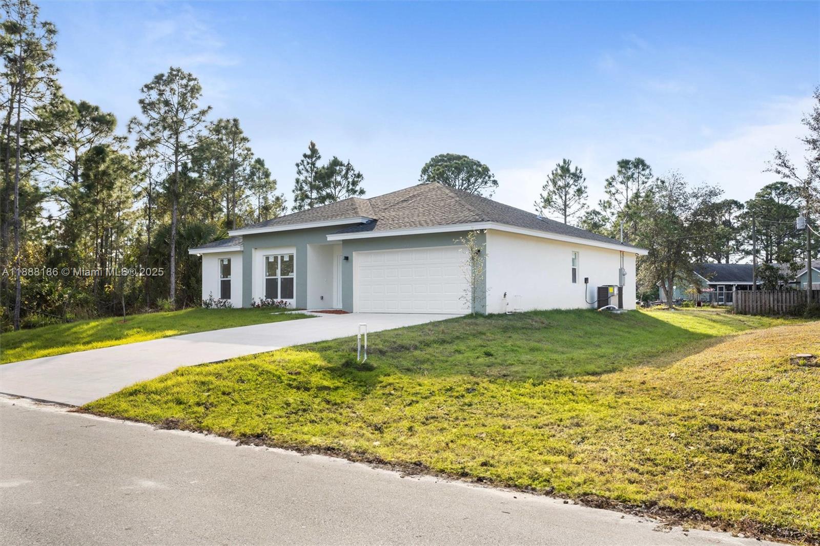 A single-story house with a white and light green exterior features a two-car garage — 1150 SE Tarleton St, Palm Bay FL 32909, PALM BAY, FL