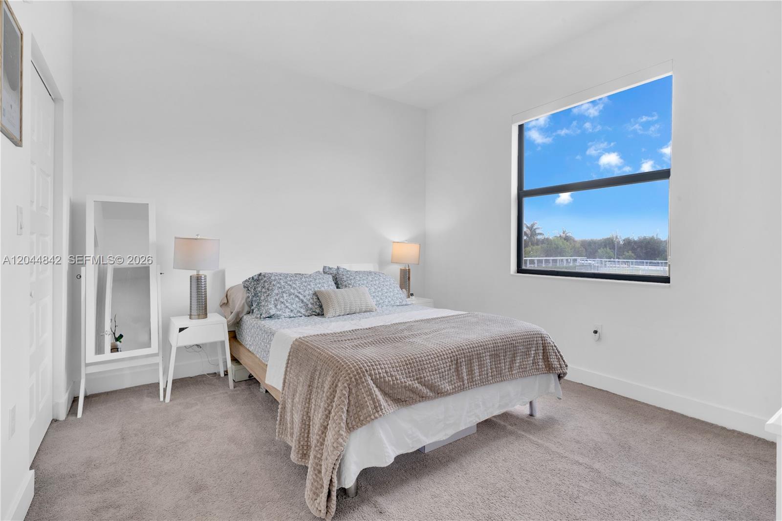 A bedroom features a bed with a tan blanket, a mirror, and a large window — 7819 NW 104th Ave # 23, Doral FL 33178, DORAL, FL