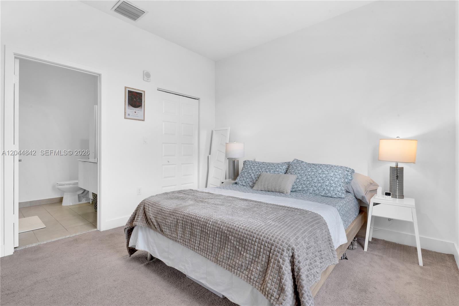A bedroom features a bed with patterned bedding, a white nightstand, and an attached bathroom — 7819 NW 104th Ave # 23, Doral FL 33178, DORAL, FL