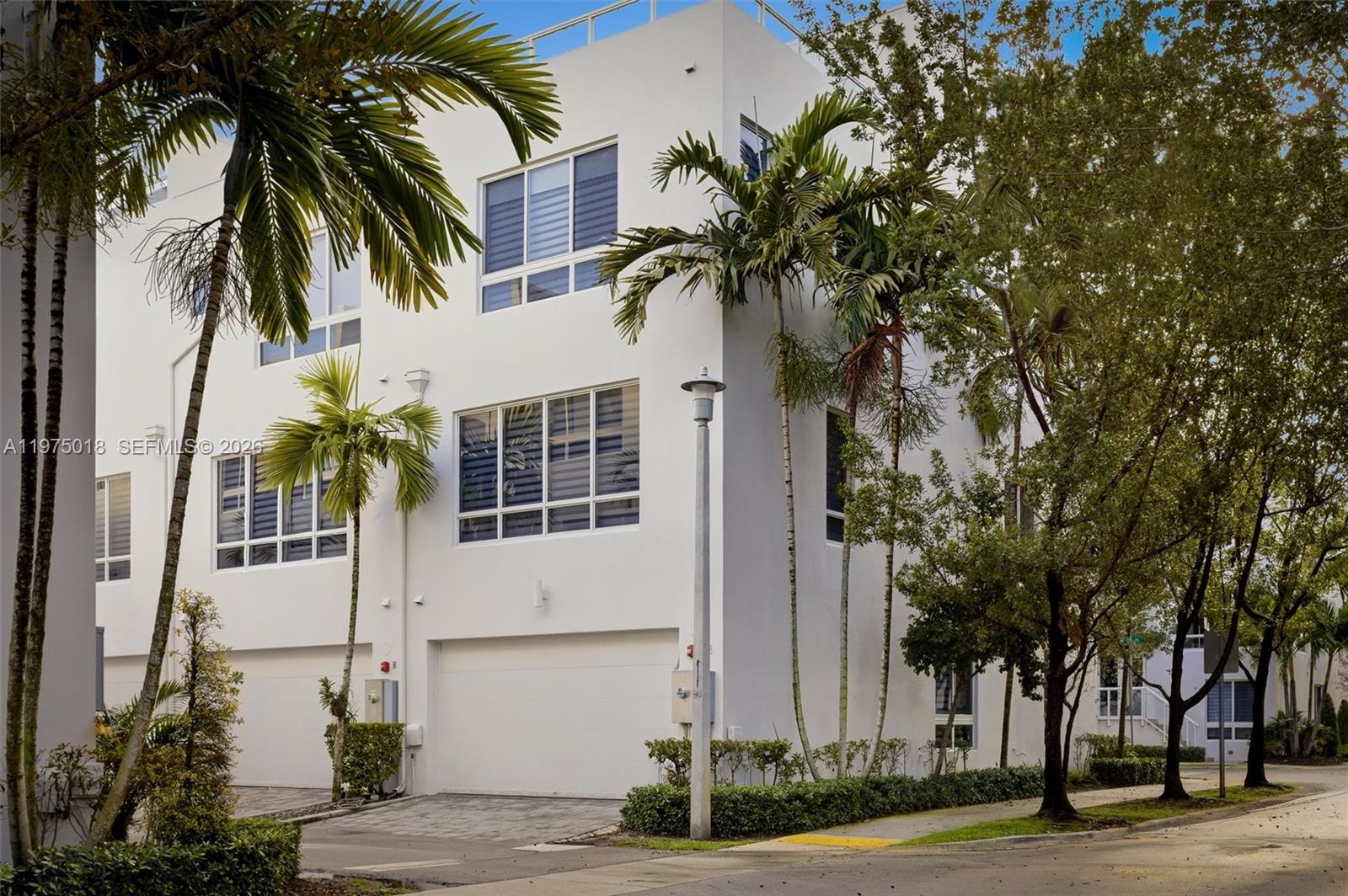 A three-story white modern townhouse with a garage and palm trees on a street — 6671 NW 105th Pl # 6671, Doral FL 33178, DORAL, FL
