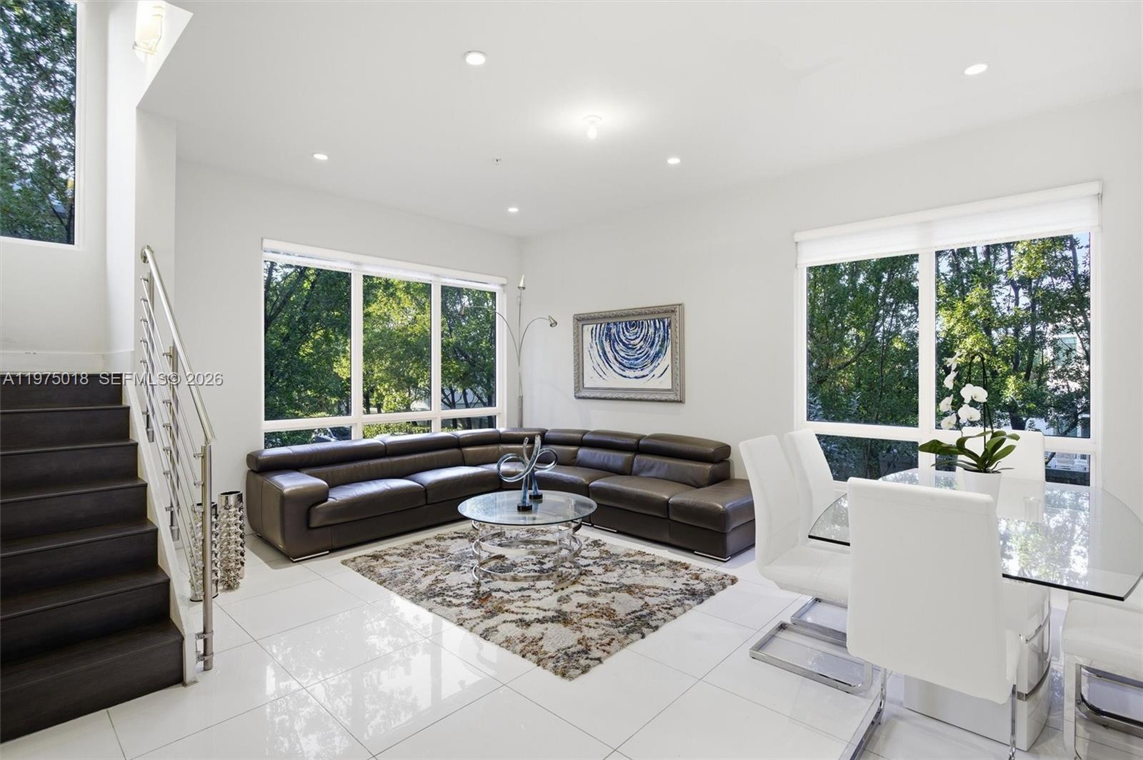 A modern living and dining area features white tile floors, a dark sectional, and large windows — 6671 NW 105th Pl # 6671, Doral FL 33178, DORAL, FL
