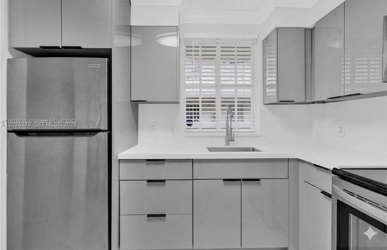 A modern kitchen features gray cabinets, stainless steel appliances, and white countertops — 6135 NW 186th St # 202, Hialeah FL 33015, HIALEAH, FL