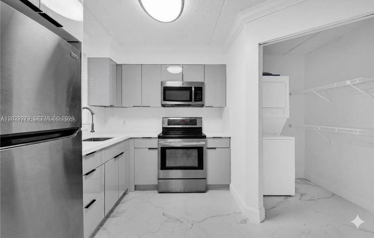 A modern kitchen features stainless steel appliances, grey cabinetry, and white marble-patterned flooring — 6135 NW 186th St # 202, Hialeah FL 33015, HIALEAH, FL