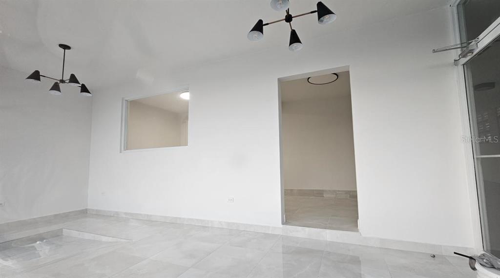 A bright room features white walls, light-colored tile flooring, two modern light fixtures, and a doorway — 863 CARR. 876, TRUJILLO ALTO, PR