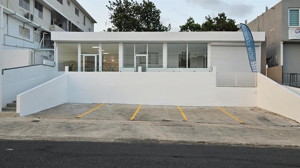 A white commercial building features a glass storefront above a four-space paved parking lot — 863 CARR. 876, TRUJILLO ALTO, PR
