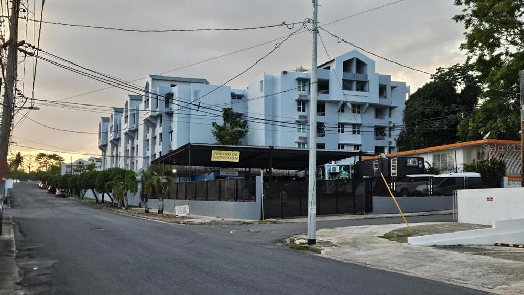 A multi-story light blue apartment building stands behind a vehicle inspection center on a street — 863 CARR. 876, TRUJILLO ALTO, PR