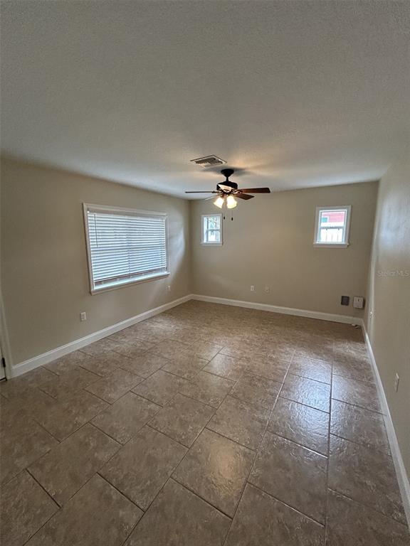 A room with beige walls, tile flooring, a ceiling fan, and two windows with blinds — 119 W 10TH AVENUE, MOUNT DORA, FL