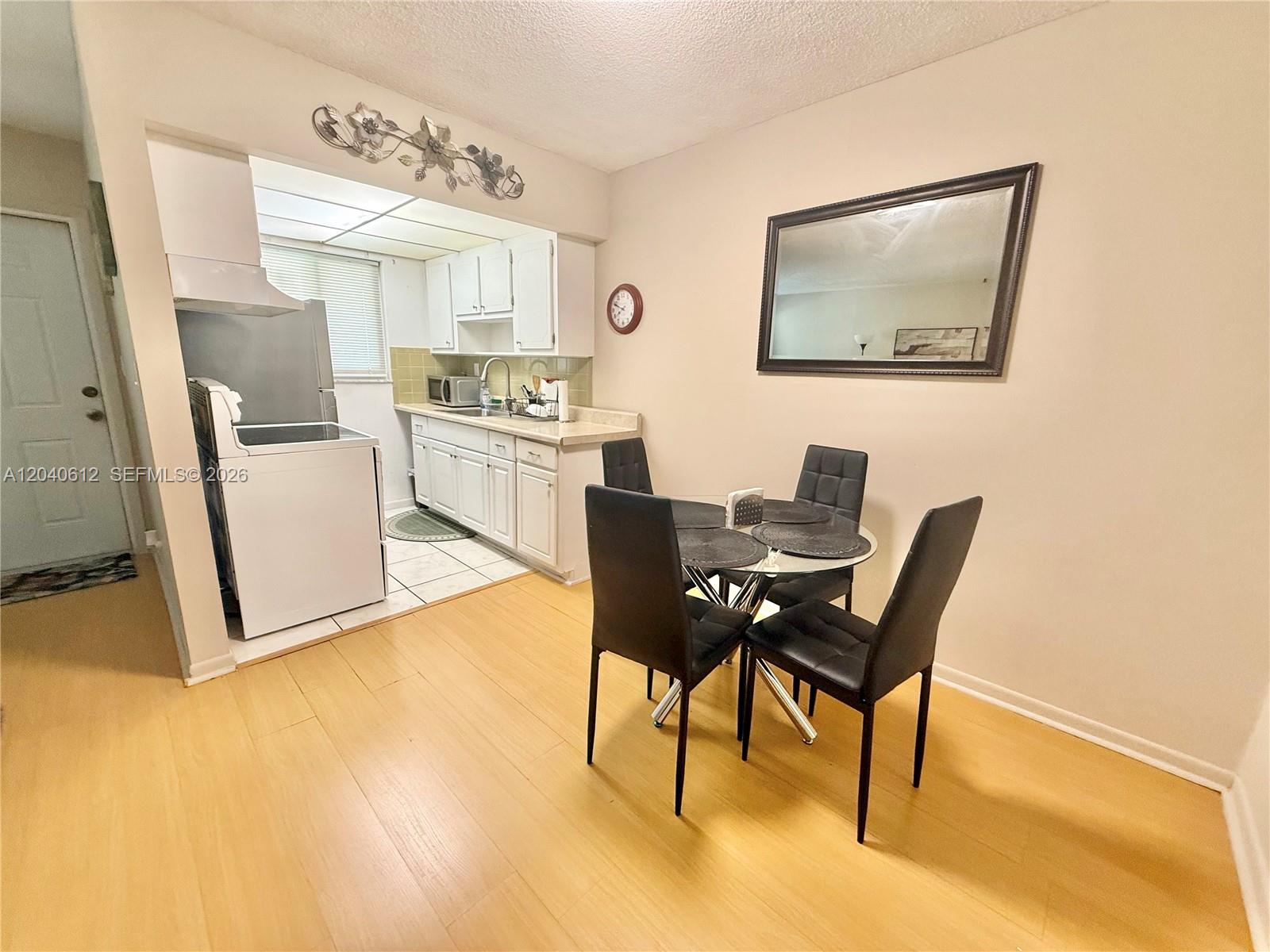 A dining area with a glass table and four chairs sits adjacent to a kitchen — 2145 Pierce St # 206, Hollywood FL 33020, HOLLYWOOD, FL
