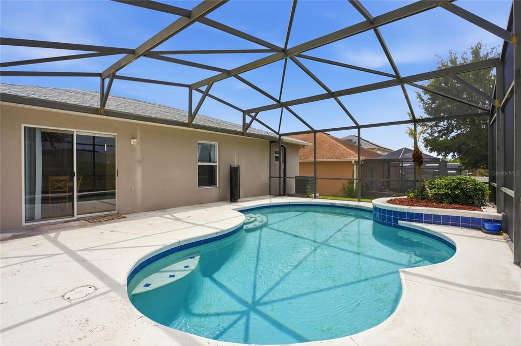 A swimming pool with a raised planter is enclosed by a screened lanai — 226 KESWICK AVENUE, DAVENPORT, FL