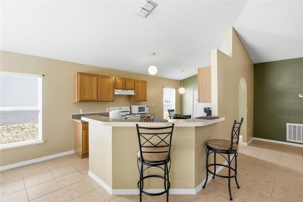 A kitchen with light wood cabinets, a breakfast bar, and tile flooring — 226 KESWICK AVENUE, DAVENPORT, FL