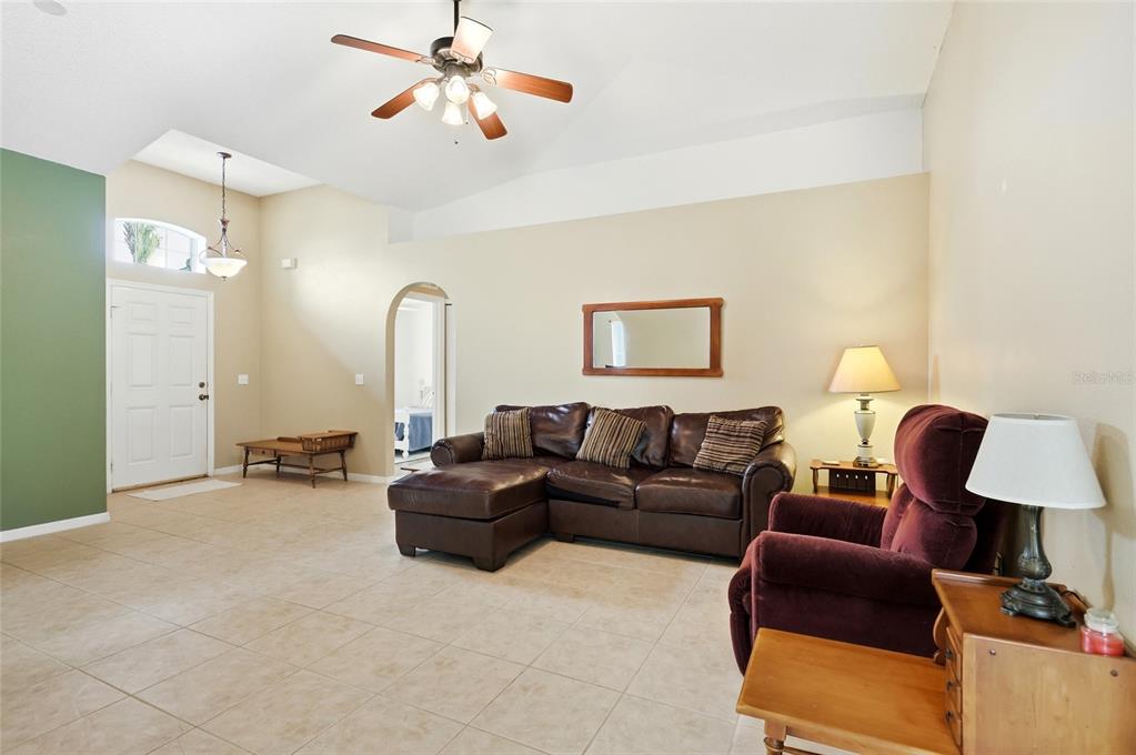 A living room with tile flooring, a vaulted ceiling, a brown sectional, and a recliner — 226 KESWICK AVENUE, DAVENPORT, FL