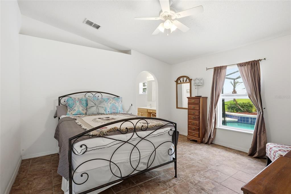 A bedroom features a metal bed frame, tile flooring, and a view of a pool — 226 KESWICK AVENUE, DAVENPORT, FL