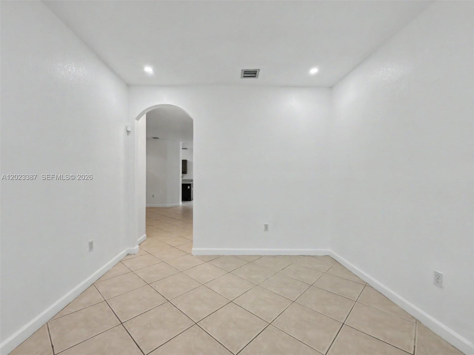 A minimalist room with white walls, tile flooring, and an arched doorway leading to another area — 9267 SW 220th Ter, Cutler Bay FL 33190, CUTLER BAY, FL