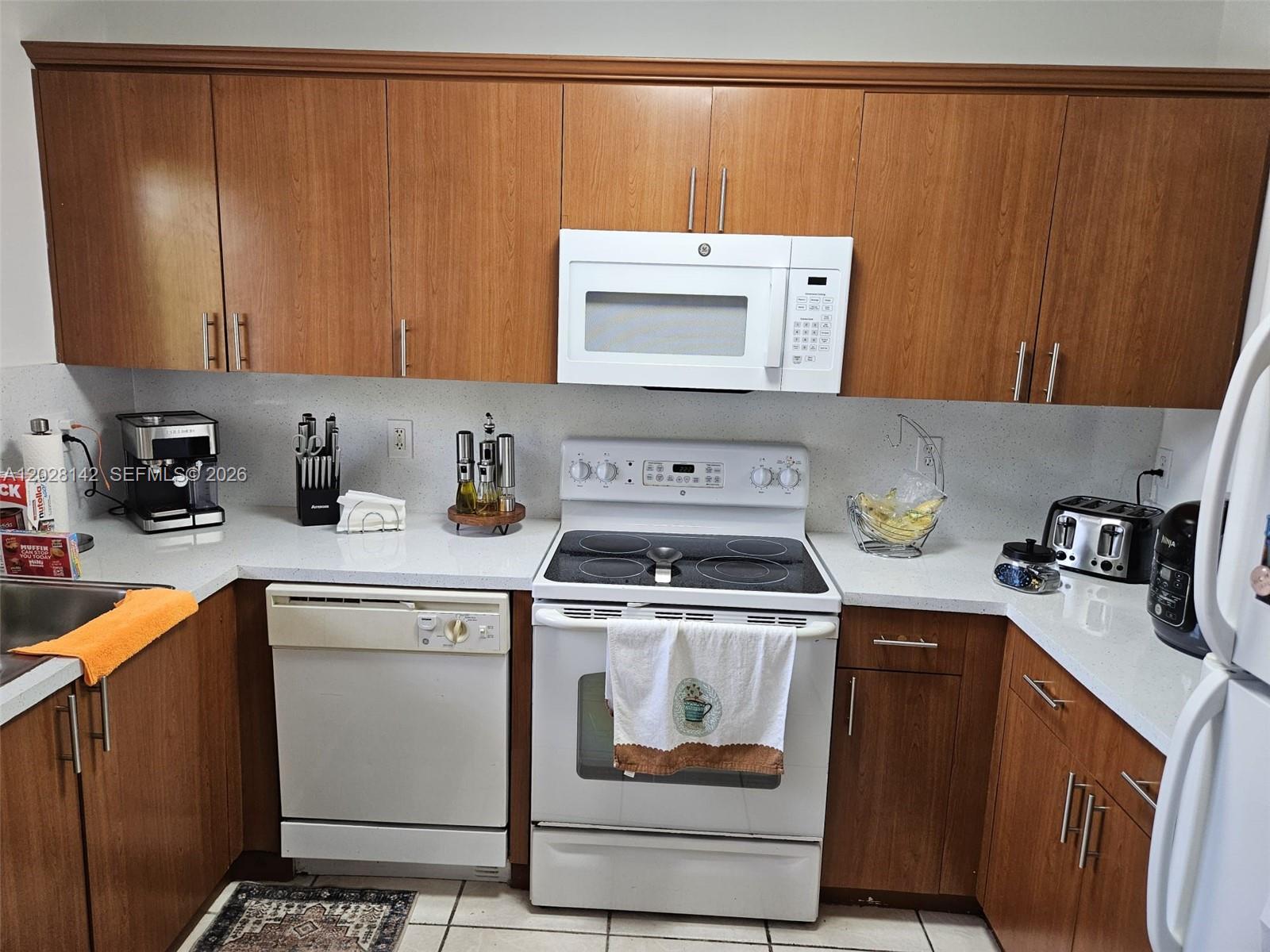 A kitchen features wood cabinets, white appliances, and light-colored countertops — 8394 SW 152nd Ave # 34, Miami FL 33193, MIAMI, FL