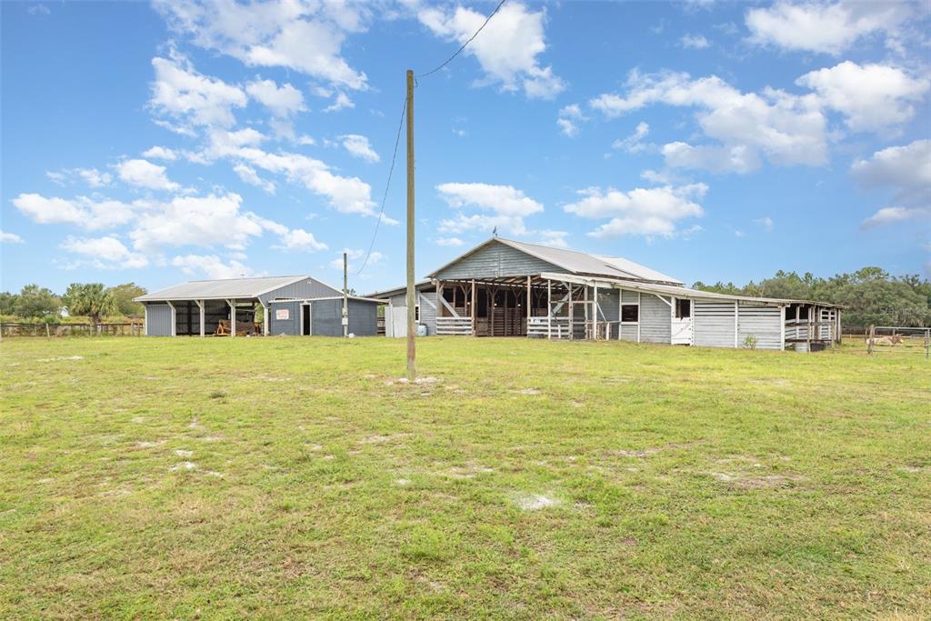 A large wooden barn and a smaller shed stand in a grassy, open field — 1374 E OHIO AVENUE, LAKE HELEN, FL