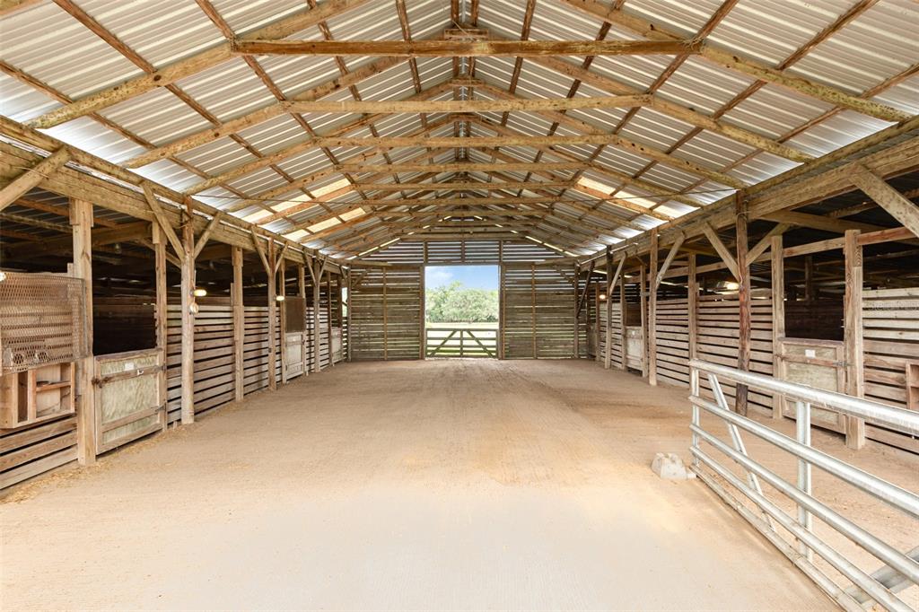An interior view of a wooden horse barn with multiple stalls and a dirt floor — 1374 E OHIO AVENUE, LAKE HELEN, FL