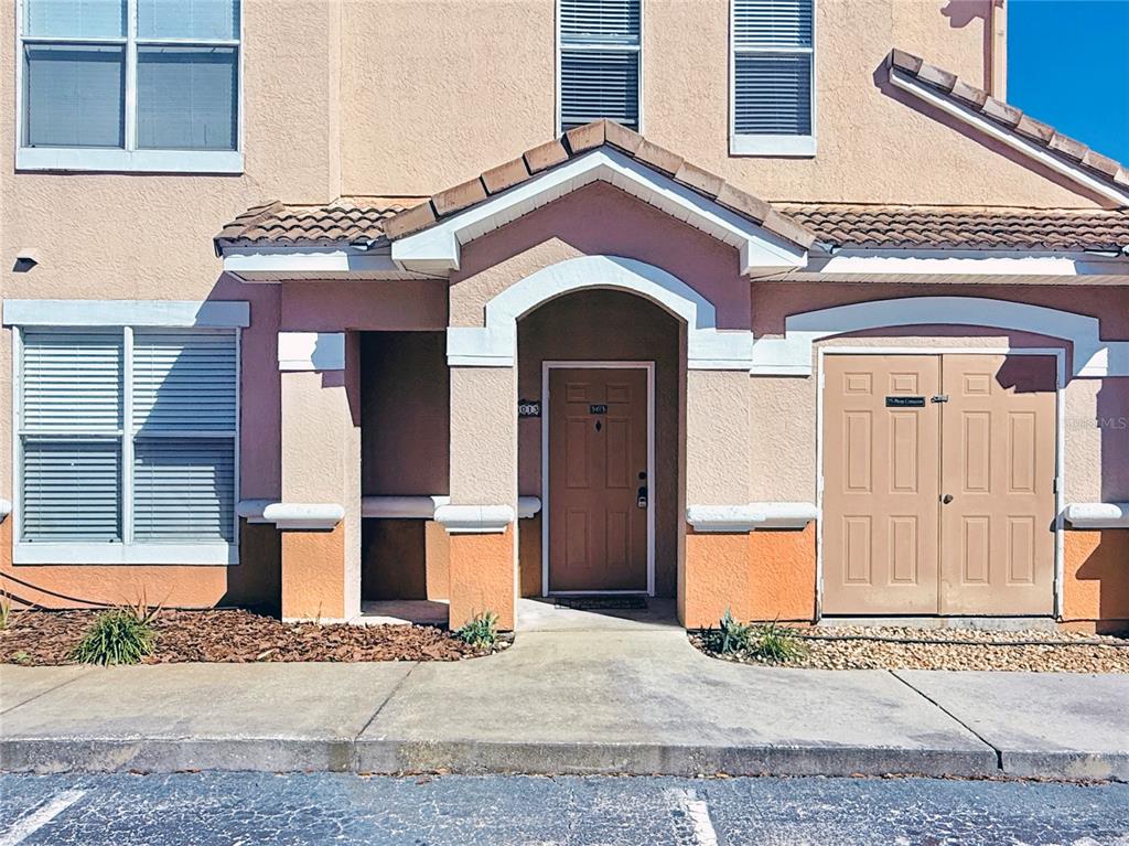 The exterior of a two-story tan townhouse features a covered entryway and a storage closet — 18013 VILLA CREEK DRIVE, TAMPA, FL