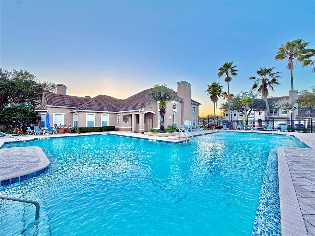 A large swimming pool sits in front of a multi-story building with palm trees — 18013 VILLA CREEK DRIVE, TAMPA, FL