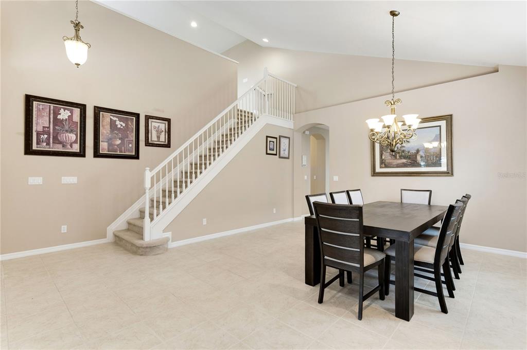 A dining area with a dark wood table and chairs sits beside a carpeted staircase — 4284 RIVER BANK WAY, PUNTA GORDA, FL