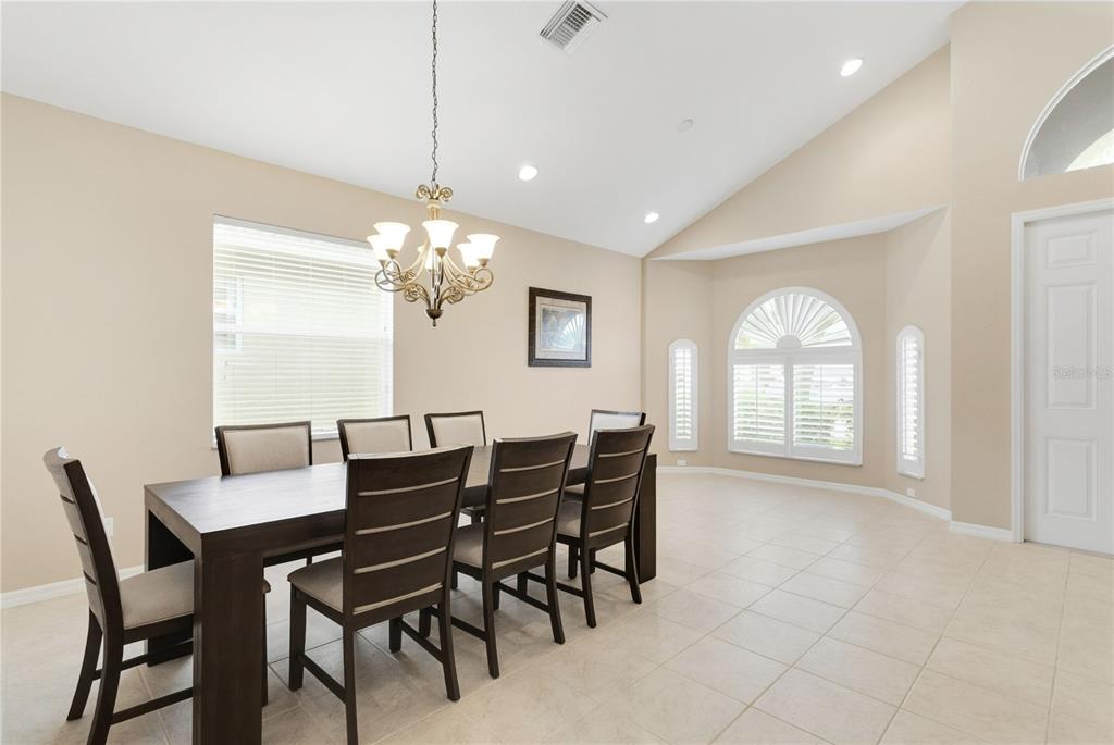 A dining room features a dark wood table with six chairs, tile flooring, and vaulted ceilings — 4284 RIVER BANK WAY, PUNTA GORDA, FL