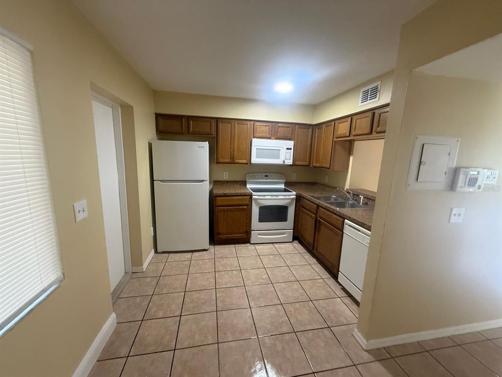 A kitchen with wood cabinets, white appliances, brown countertops, and light-colored tile flooring — 213 S MOSS ROAD, WINTER SPRINGS, FL