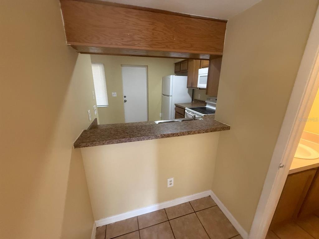 A kitchen pass-through window with a laminate countertop overlooks a kitchen with white appliances — 213 S MOSS ROAD, WINTER SPRINGS, FL