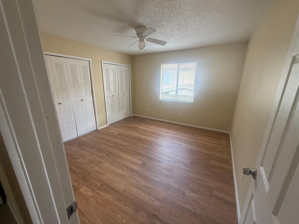 An empty bedroom features light wood-look flooring, two white louvered closets, and a ceiling fan — 213 S MOSS ROAD, WINTER SPRINGS, FL