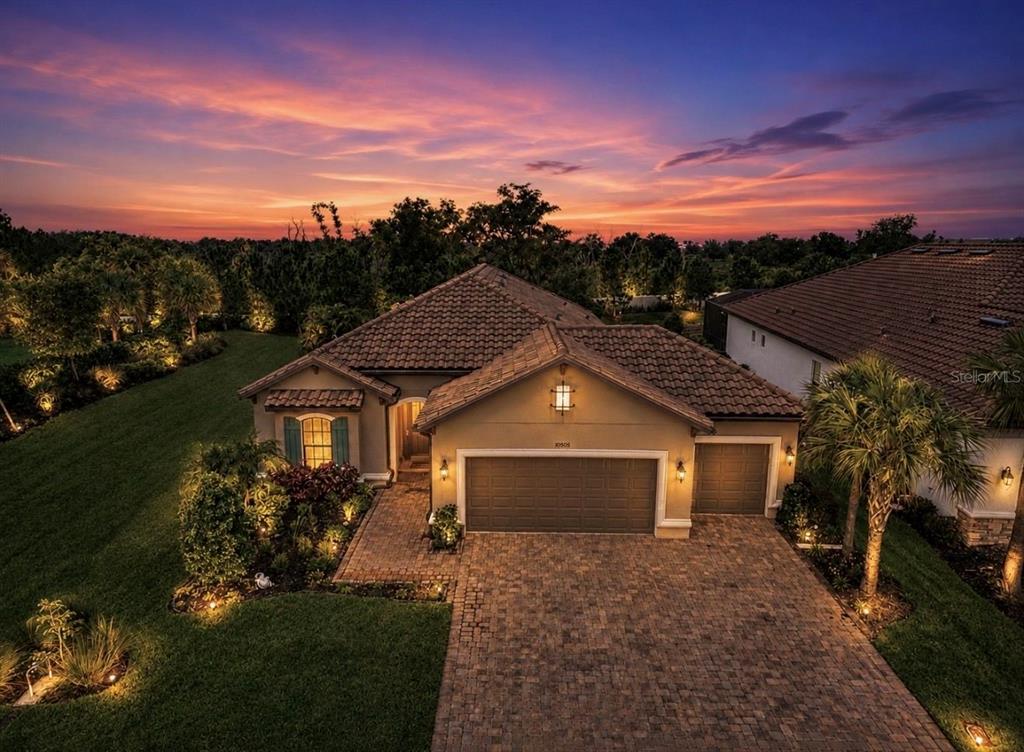 An aerial view of a single-story house with a tiled roof and brick driveway at sunset — 10505 WICKER PARK PLACE, PALMETTO, FL