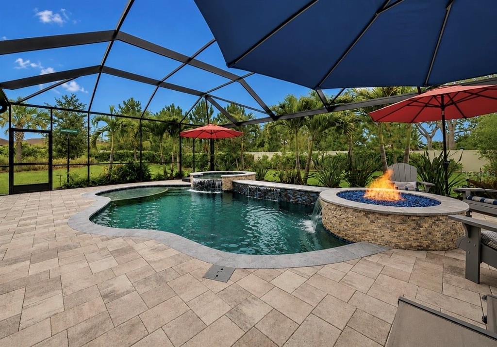 A screened-in pool area features a fire pit, a hot tub, and a waterfall feature — 10505 WICKER PARK PLACE, PALMETTO, FL