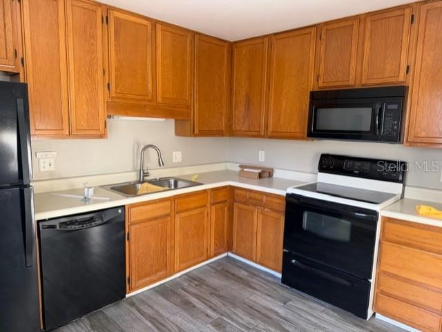 A kitchen features oak cabinets, black appliances, and light-colored countertops over wood-look flooring — 8209 OLYMPIA COURT UNIT 8209, LONGWOOD, FL