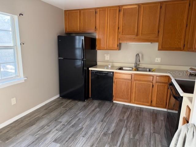 A kitchen features wood cabinets, a black refrigerator, a dishwasher, and gray wood-look flooring — 8209 OLYMPIA COURT UNIT 8209, LONGWOOD, FL