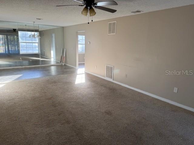 A spacious living room features beige carpeting, a ceiling fan, and a large mirrored wall — 8209 OLYMPIA COURT UNIT 8209, LONGWOOD, FL
