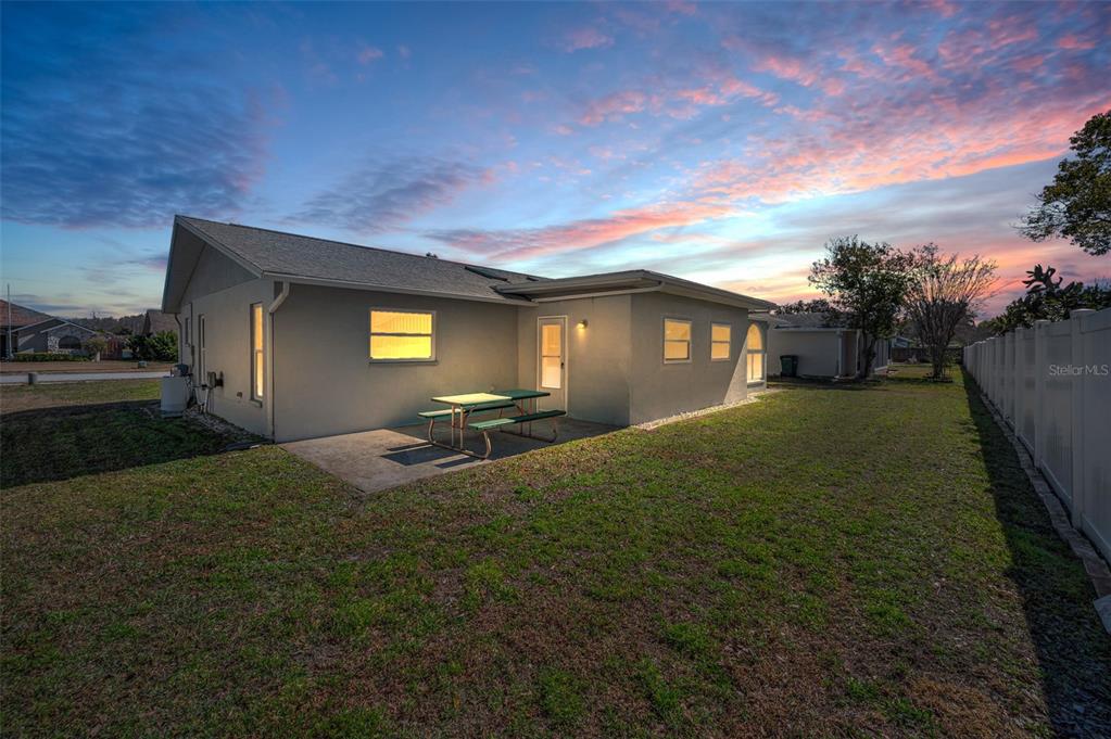 The exterior of a single-story house features a concrete patio with a picnic table — 4745 SWALLOWTAIL DRIVE, NEW PORT RICHEY, FL