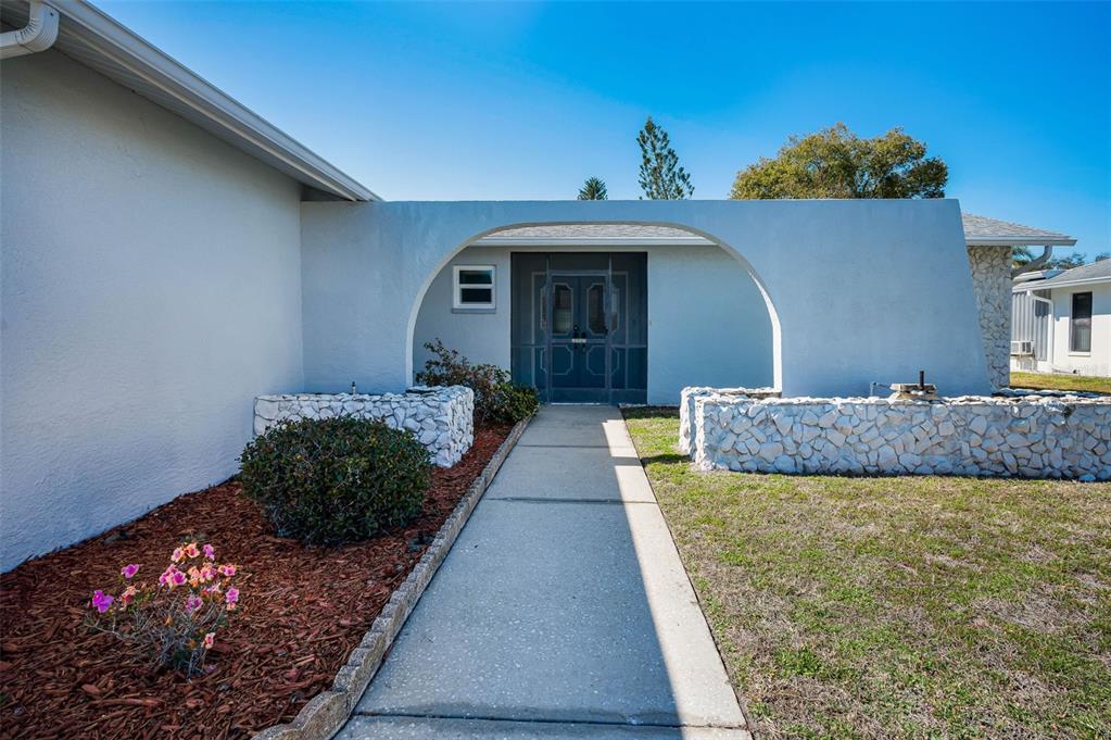 A concrete walkway leads to a front entrance framed by a large white archway — 4745 SWALLOWTAIL DRIVE, NEW PORT RICHEY, FL