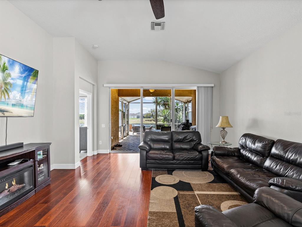 A living room features dark leather sofas, a fireplace console, hardwood floors, and sliding glass doors — 13744 TRULL WAY, HUDSON, FL