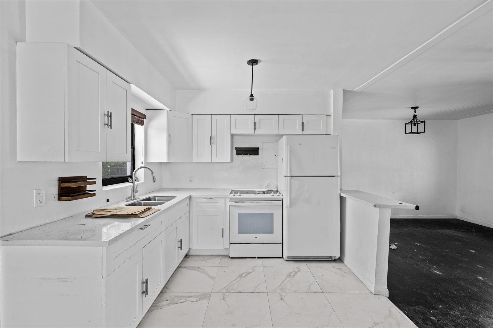 A white kitchen features marble-look tile floors, white cabinetry, and a white refrigerator — 515 NW 88th Street, El Portal FL 33150, EL PORTAL, FL