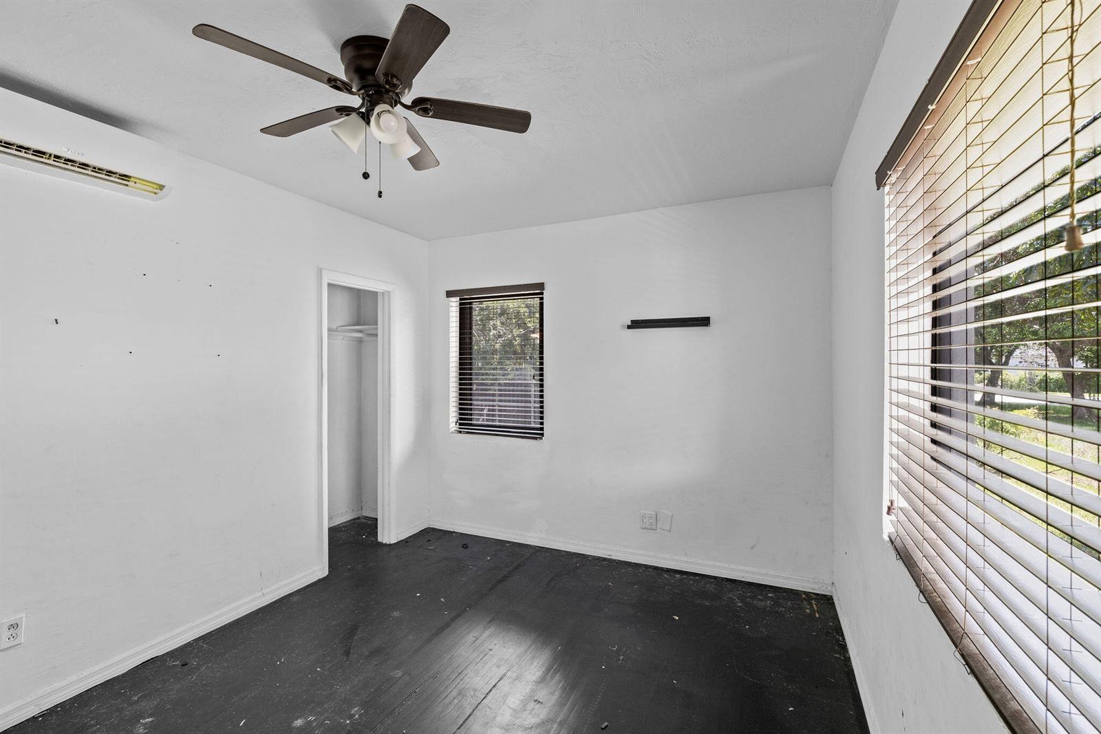 An empty bedroom features white walls, dark wood flooring, a ceiling fan, and window blinds — 515 NW 88th Street, El Portal FL 33150, EL PORTAL, FL