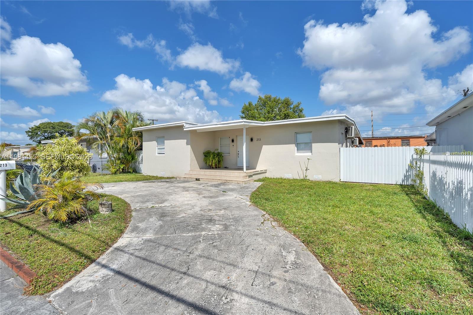 A single-story house with a concrete driveway, a front porch, and a white fence — 213 W 20th St, Hialeah FL 33010, HIALEAH, FL