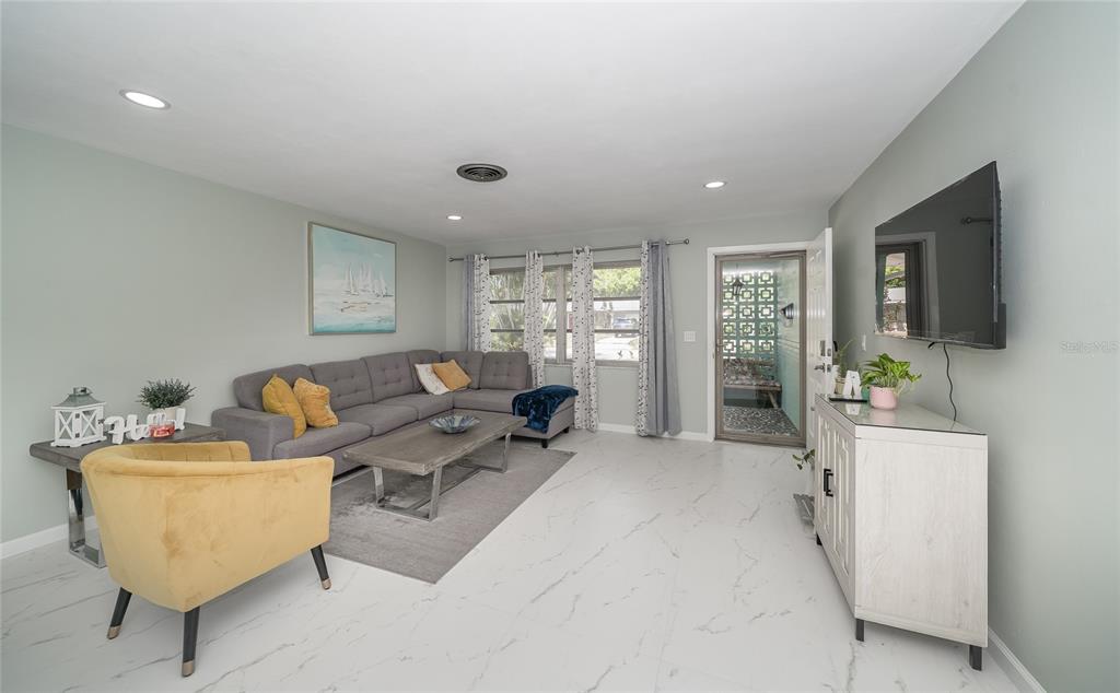 A living room features a gray sectional sofa, a yellow armchair, and white tile flooring — 2063 DUNSTON COVE ROAD, CLEARWATER, FL