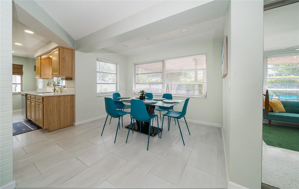 A dining area with a glass table, teal chairs, and light tile flooring near a kitchen — 2063 DUNSTON COVE ROAD, CLEARWATER, FL