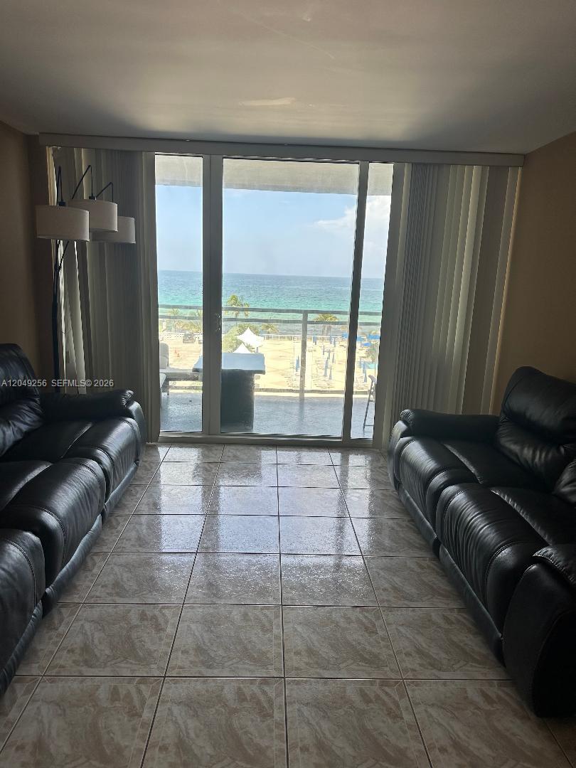 A living room with two black leather sofas, tile flooring, and a balcony overlooking the ocean — 2030 S Ocean Dr # 416, Hallandale Beach FL 33009, HALLANDALE BEACH, FL