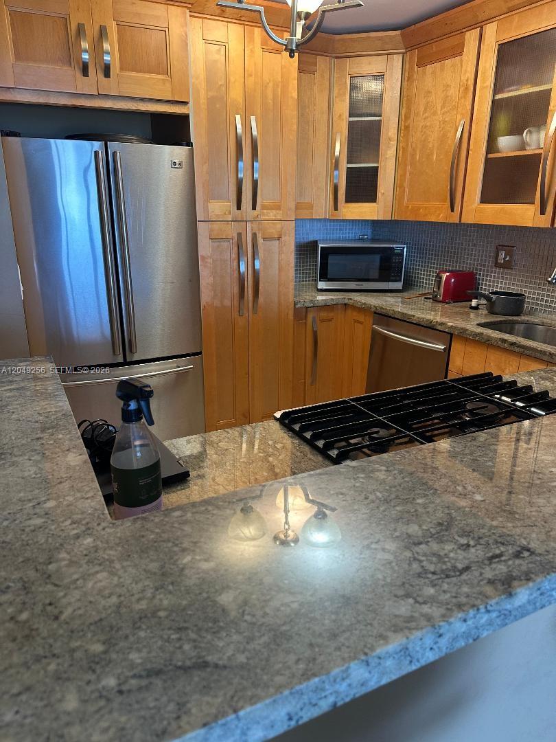 A kitchen features light wood cabinets, stainless steel appliances, and a granite countertop peninsula — 2030 S Ocean Dr # 416, Hallandale Beach FL 33009, HALLANDALE BEACH, FL