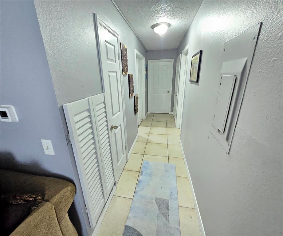 A hallway with light-colored tile flooring, gray walls, and several white interior doors — 4073 DIJON DRIVE UNIT 4073J, ORLANDO, FL