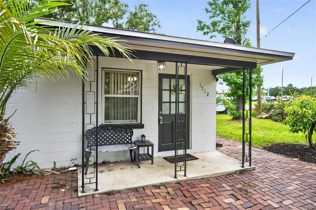 A small white building with a covered porch, a black door, and a brick patio — 1712 LAKE BROWN DRIVE, HAINES CITY, FL