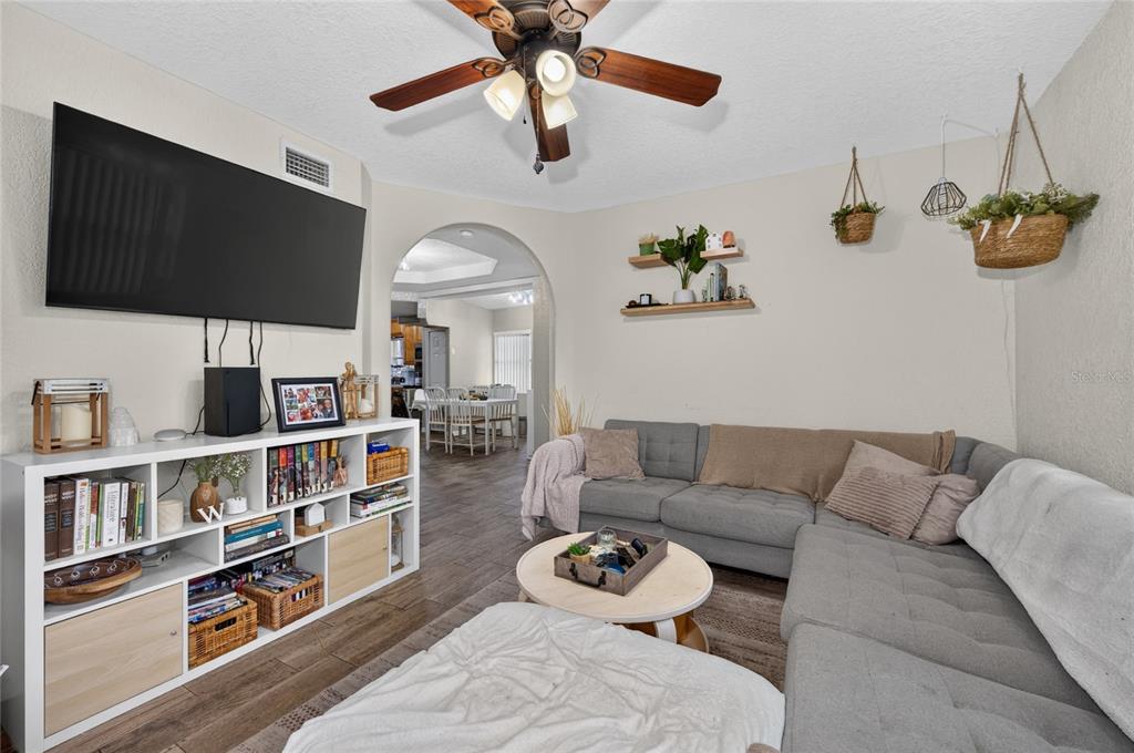 A living room features a grey sectional sofa, a white media console, and a ceiling fan — 1712 LAKE BROWN DRIVE, HAINES CITY, FL
