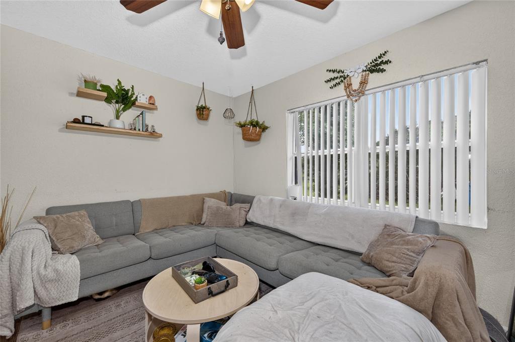 A living room features a gray sectional sofa, a round coffee table, and wall-mounted shelving — 1712 LAKE BROWN DRIVE, HAINES CITY, FL