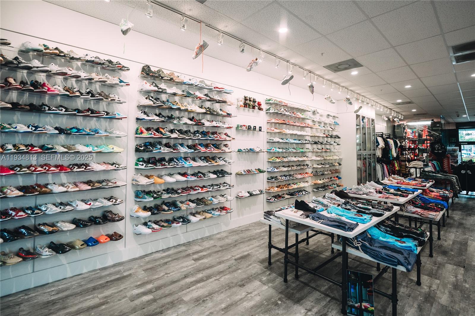 A retail store features extensive wall-mounted shelving displaying numerous sneakers and tables with folded apparel — 12700 SW 128th St #106, Miami FL 33186, MIAMI, FL