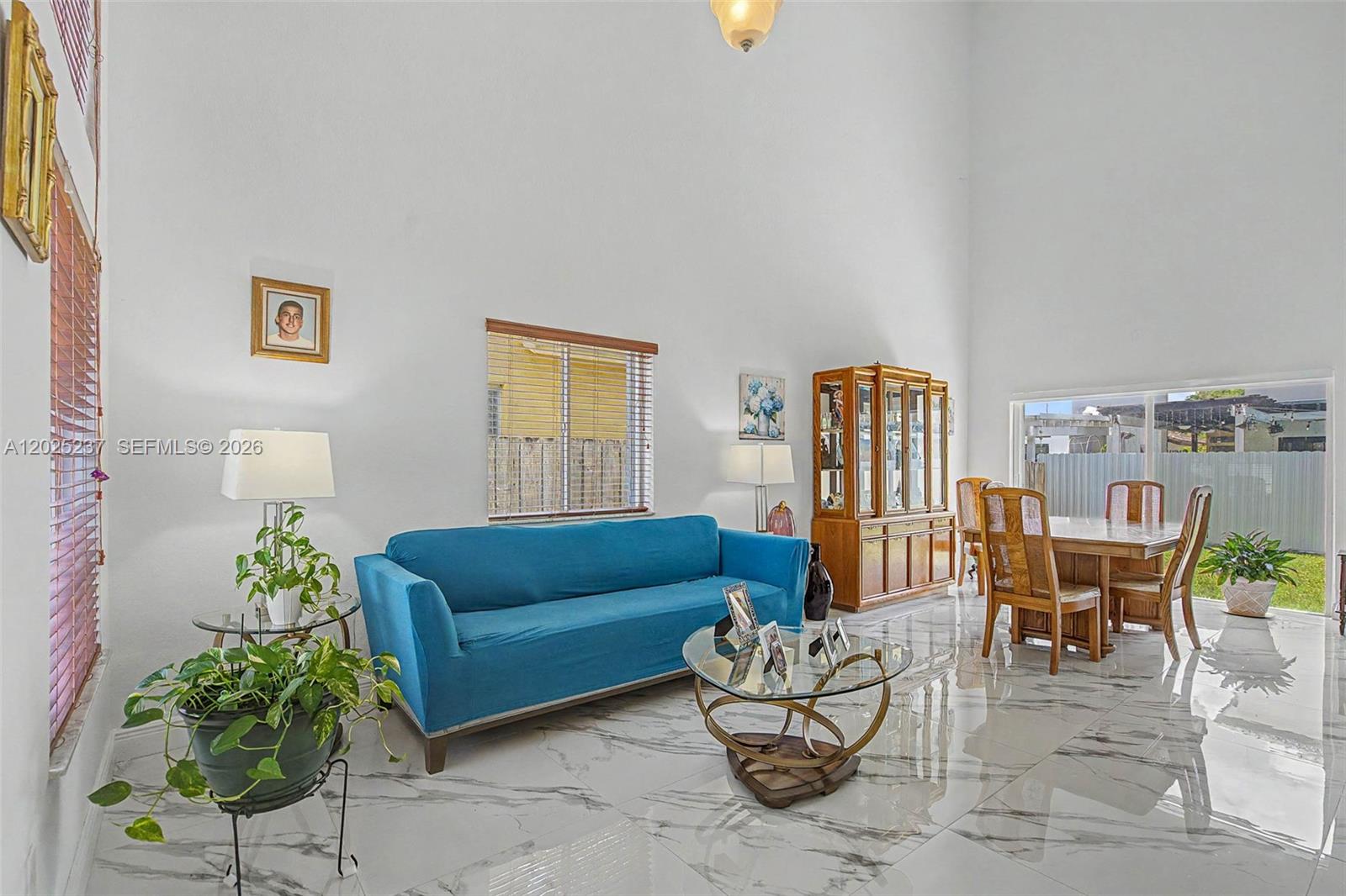 A bright living and dining area features high ceilings, white marble floors, and blue furniture — 1551 SW 154th Ct, Miami FL 33194, MIAMI, FL