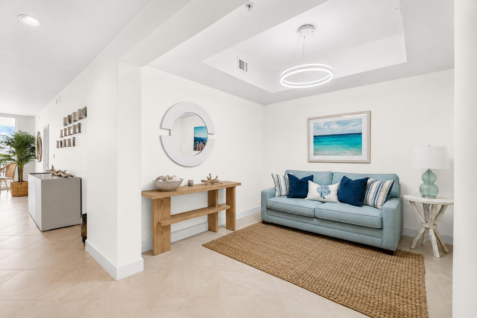 A bright living area features a light blue sofa, a wooden console table, and coastal decor — 550 Okeechobee Boulevard # 423, West Palm Beach FL 33401, WEST PALM BEACH, FL